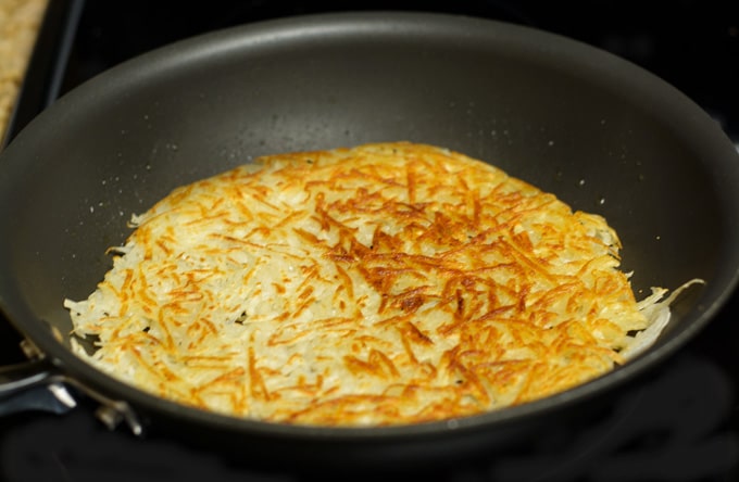 A skillet with crispy golden brown hash browns. 