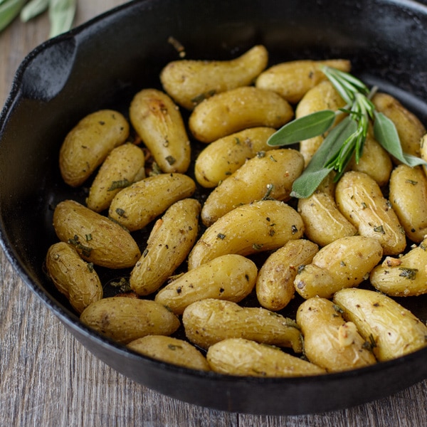 Roasted Fingerling Potatoes in a cast iron skillet with fresh herbs.
