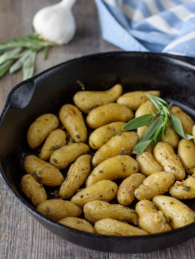 A cast iron skillet filled with roasted fingerling potatoes.