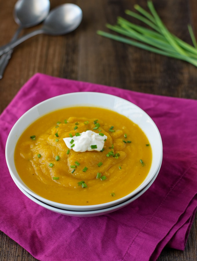 A bowl of Butternut Squash Soup topped with a dollop of sour cream and some chives. 