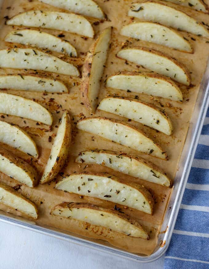 A large sheet pan lined with parchment paper and roasted potato wedges.