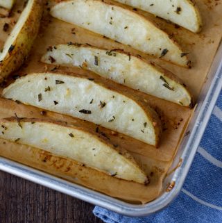 A large sheet pan with baked potato wedges.