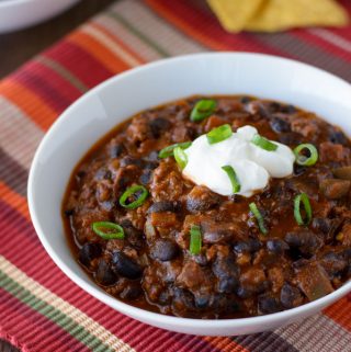 Two bowls of Chili con Carne with Beans and a few tortilla chips sitting on the side.