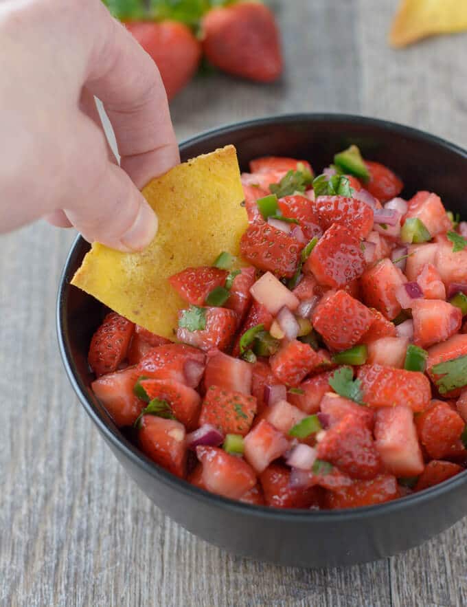 Strawberry salsa in a bowl. Tortilla chips on the side.