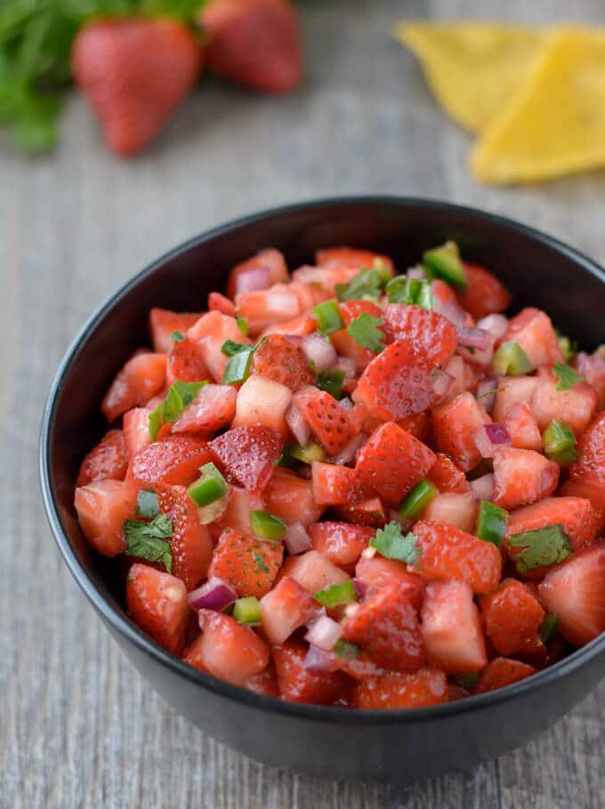 Strawberry salsa in a bowl. Tortilla chips on the side. 