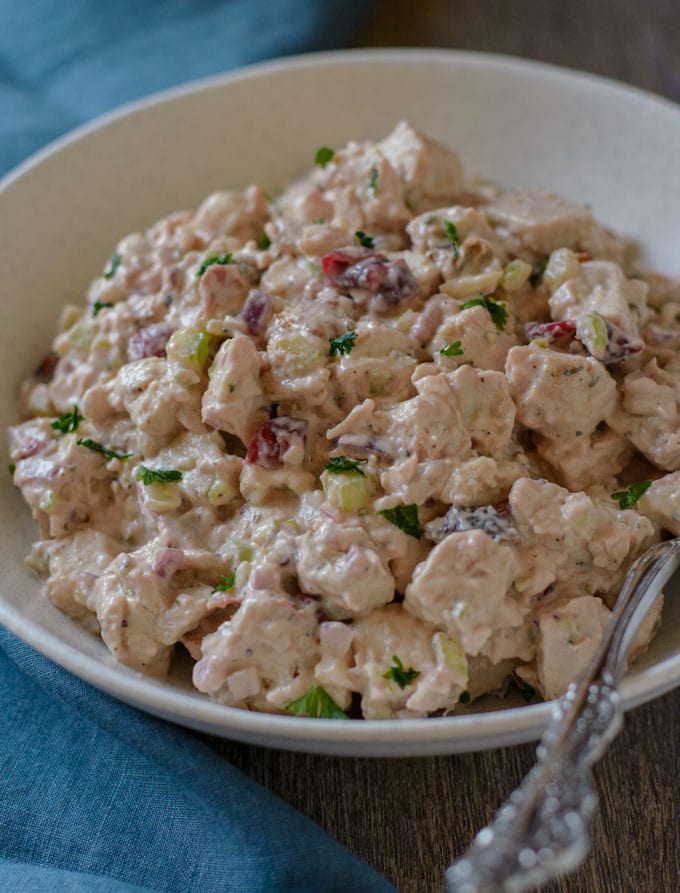 A bowl of chicken salad topped with fresh parsley. 